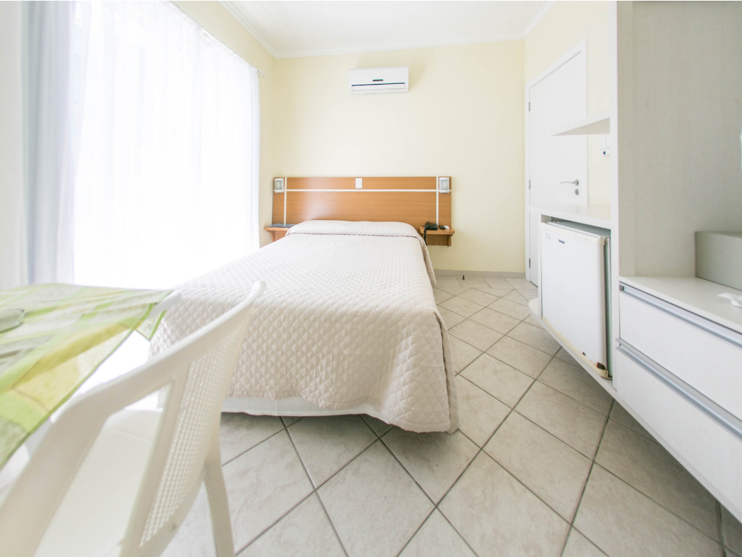 Foto da suíte com varanda no Bombinhas Praia Apart Hotel II mostrando a cama de casal, ar condicionado e frigobar