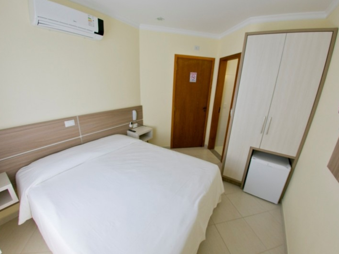 Foto da suíte sem varanda no Bombinhas Praia Apart Hotel II mostrando a cama de casal, ar condicionado e frigobar