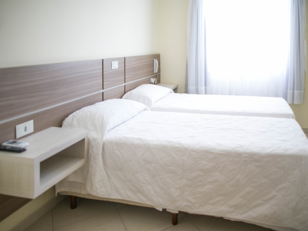 Foto da suíte sem varanda no Bombinhas Praia Apart Hotel II mostrando camas de solteiro