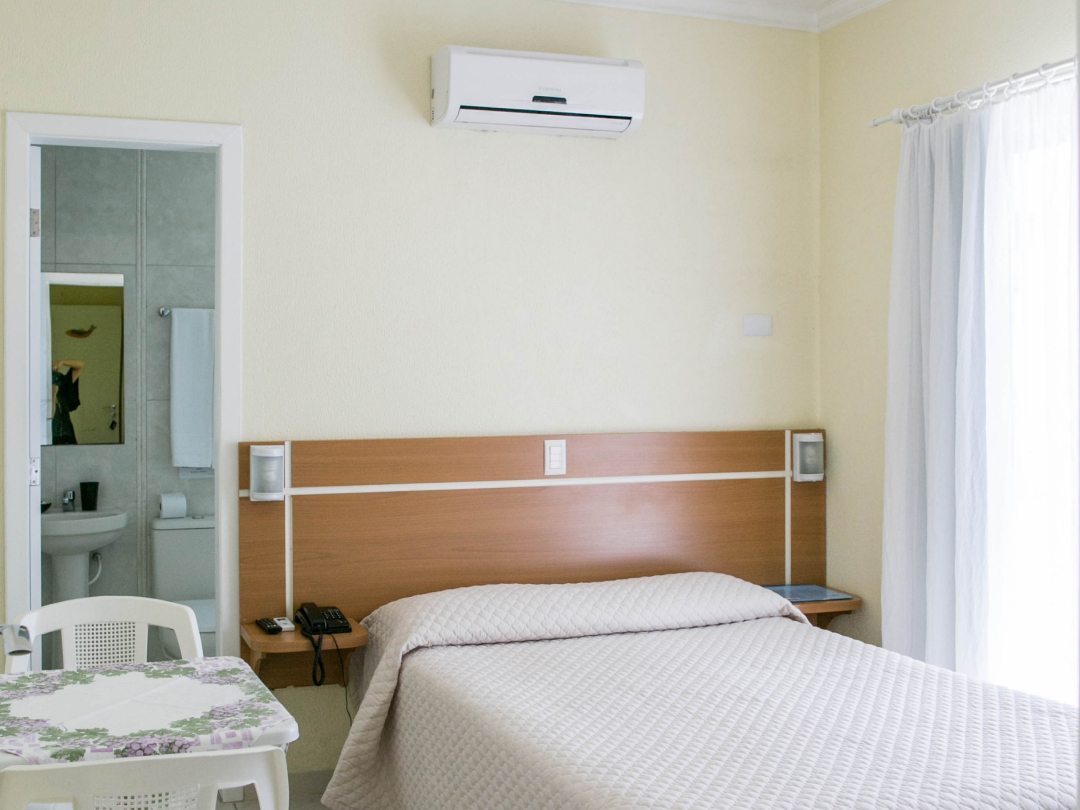 Foto da suíte família com varanda no Bombinhas Praia Apart Hotel II mostrando a cama de casal, ar condicionado e o banheiro