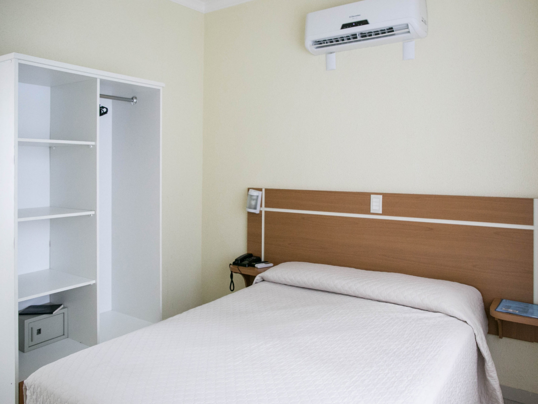 Foto do apartamento família no Bombinhas Praia Apart Hotel II mostrando a cama de casal e o ar condicionado.