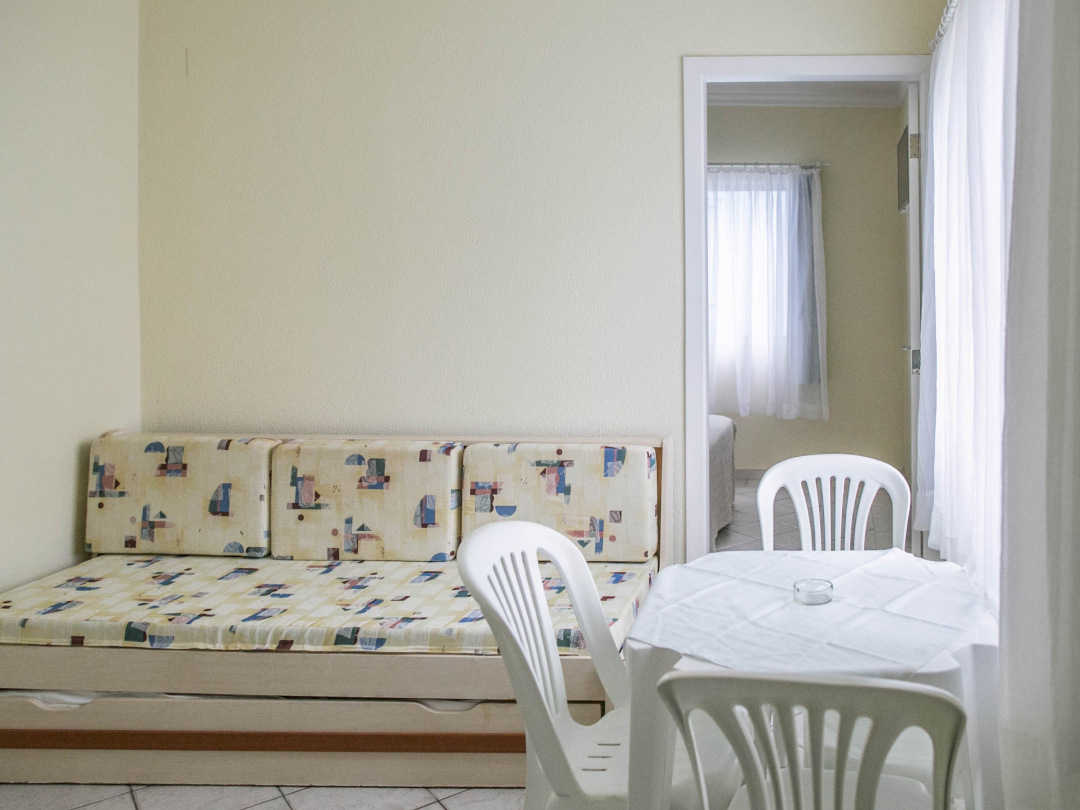 Foto do apartamento família no Bombinhas Praia Apart Hotel II mostrando a sala, o bicama, mesa e a porta do quarto
